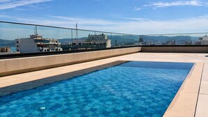 A rooftop swimming pool with a clear view of the cityscape in the background.