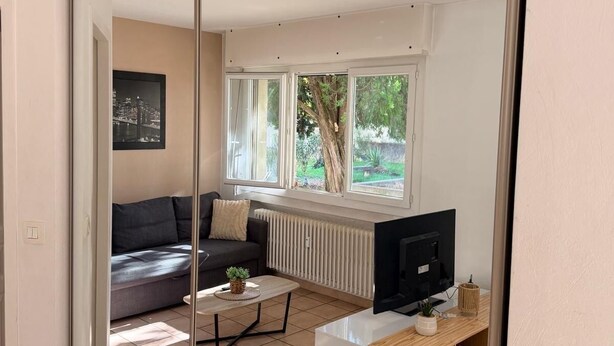 A modern living room with a sofa, coffee table, TV, and a sliding glass door leading to a balcony.