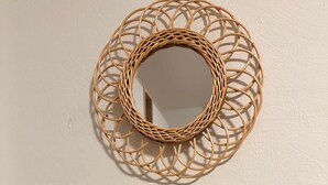 Three cylindrical containers with wooden lids and metal handles, a woven circular mirror, and a textured wall.