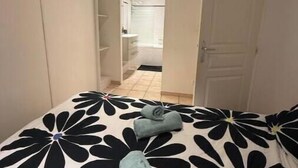 A bedroom with a bed, a wardrobe, and a bathroom visible through an open door.