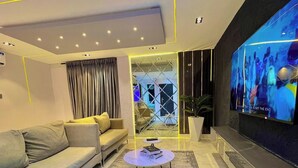 A modern living room with a sofa, a coffee table, a TV, and a patterned rug. - The Waves Apartment (Lagos)