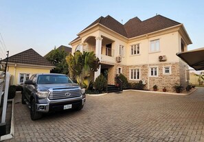 A two-story house with a driveway, a parked SUV, and a covered patio area.