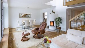 Ein modernes Wohnzimmer mit Kamin, Ledersesseln, einer Couch und einer Obstschale.