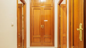 A wooden double door with a sign, a light switch, and a tiled floor. - Central Apartment in Seville (Sevilla)