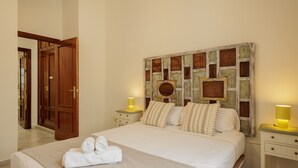A hotel room with a large bed, two bedside tables, a wooden door, and a decorative headboard. - Central Apartment in Seville (Sevilla)