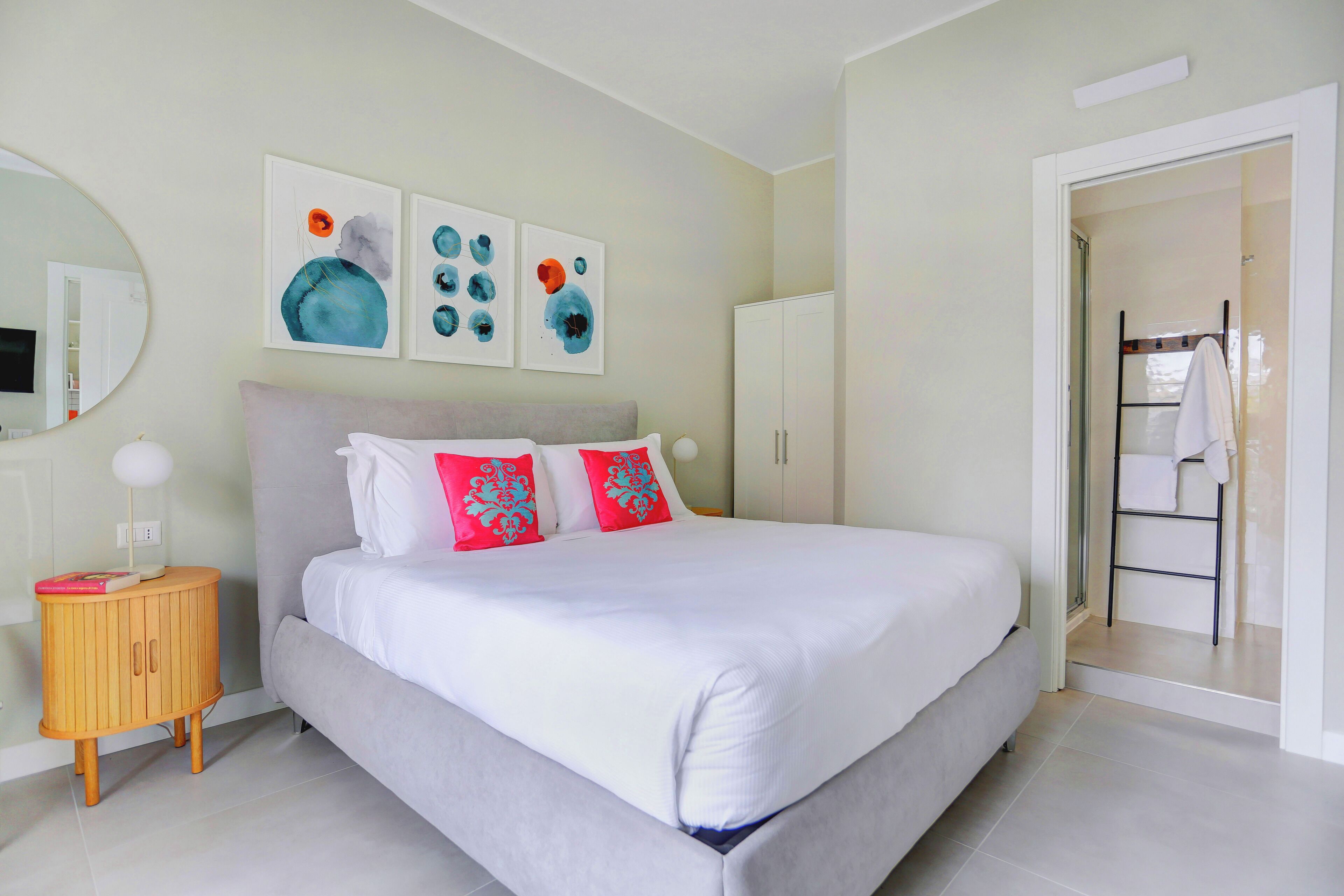 Une chambre à coucher moderne, avec un lit, une table de chevet, une armoire et une salle de bain visible à travers une porte ouverte.