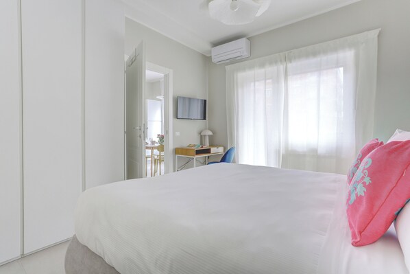 A bedroom with a bed, a desk, a chair, a TV, and a window with curtains. - San Giovanni Appia Park Modern Apartment with Balcony Metro A 10 Min City Center (Rome)