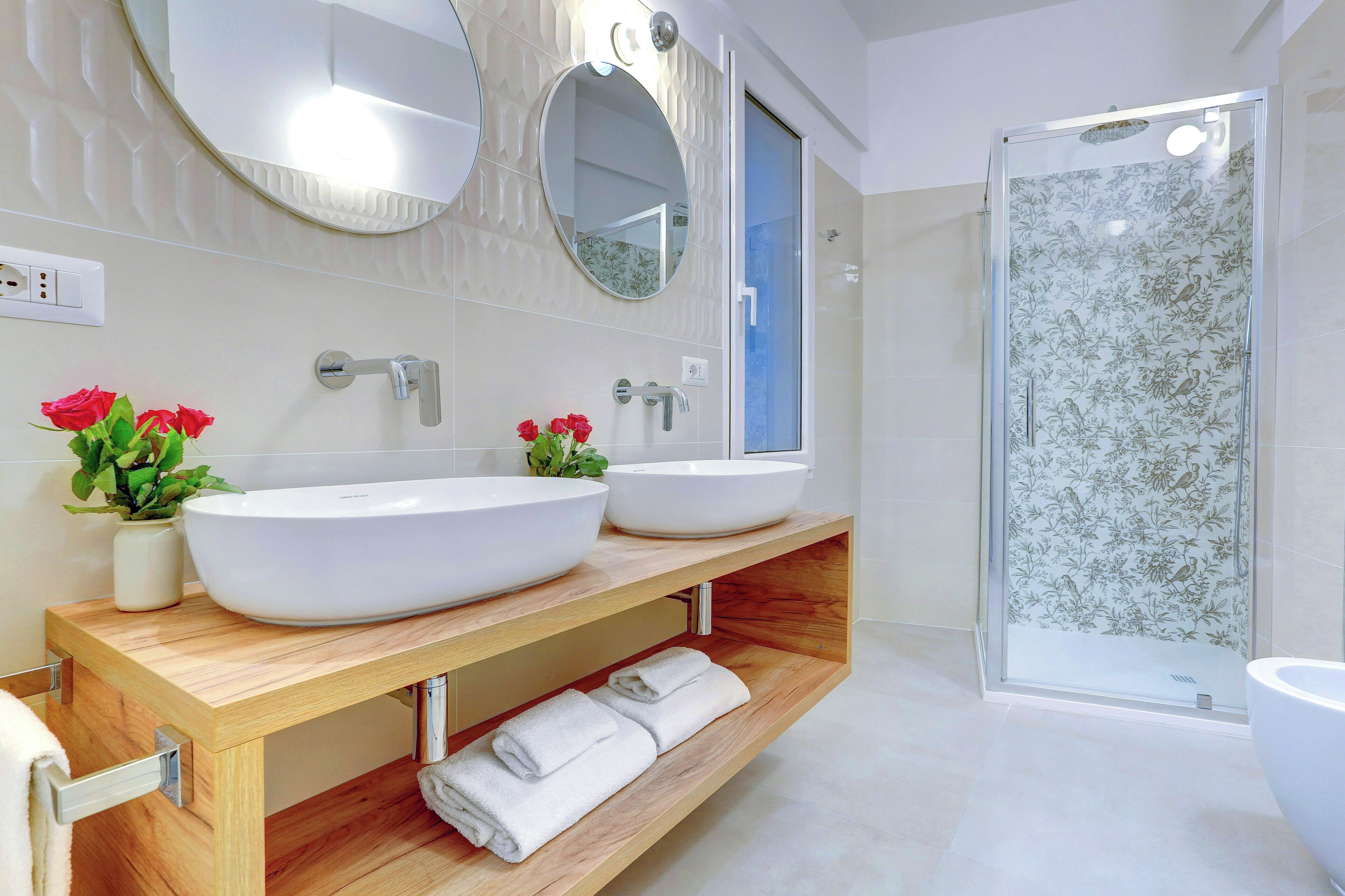 Un baño moderno con dos lavamanos, ducha y tocador con espejo.