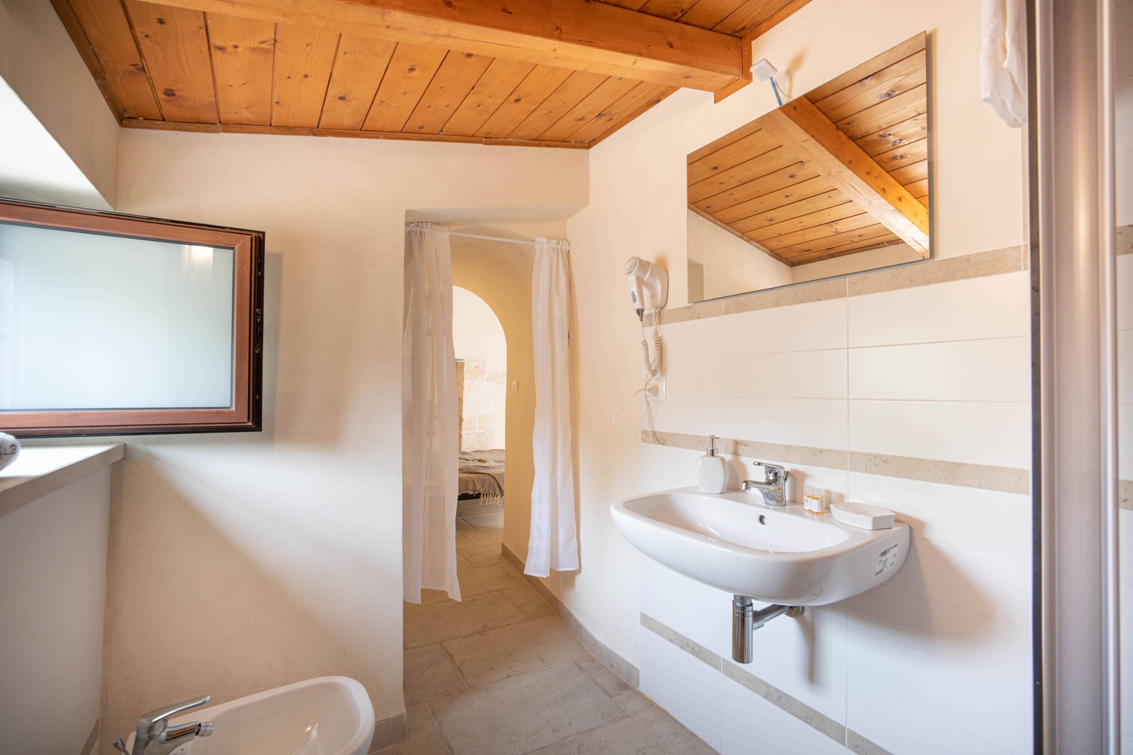 Ein Badezimmer mit Holzboden, einem großen Spiegel, einem Waschbecken und einer Duschkabine.
