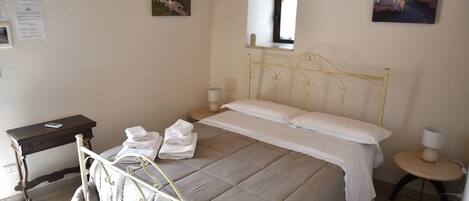 A bedroom with a bed, bedside table, lamp, and wall art.