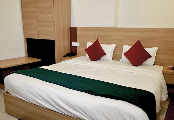 A hotel room with a large bed, a wooden headboard, a bedside table, and a TV.