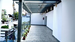 Un couloir orné d’une rambarde métallique, de plantes en pot et de luminaires suspendus.
