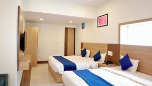 Une chambre d’hôtel avec deux lits, un bureau, une chaise et un téléviseur.