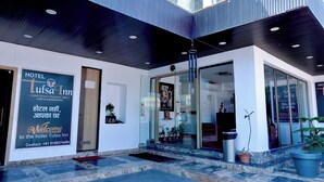 L’extérieur de l’hôtel Tulsa Inn présente un design moderne, avec une entrée en verre, des plantes en pot et un numéro de téléphone indiqué sur l’enseigne.