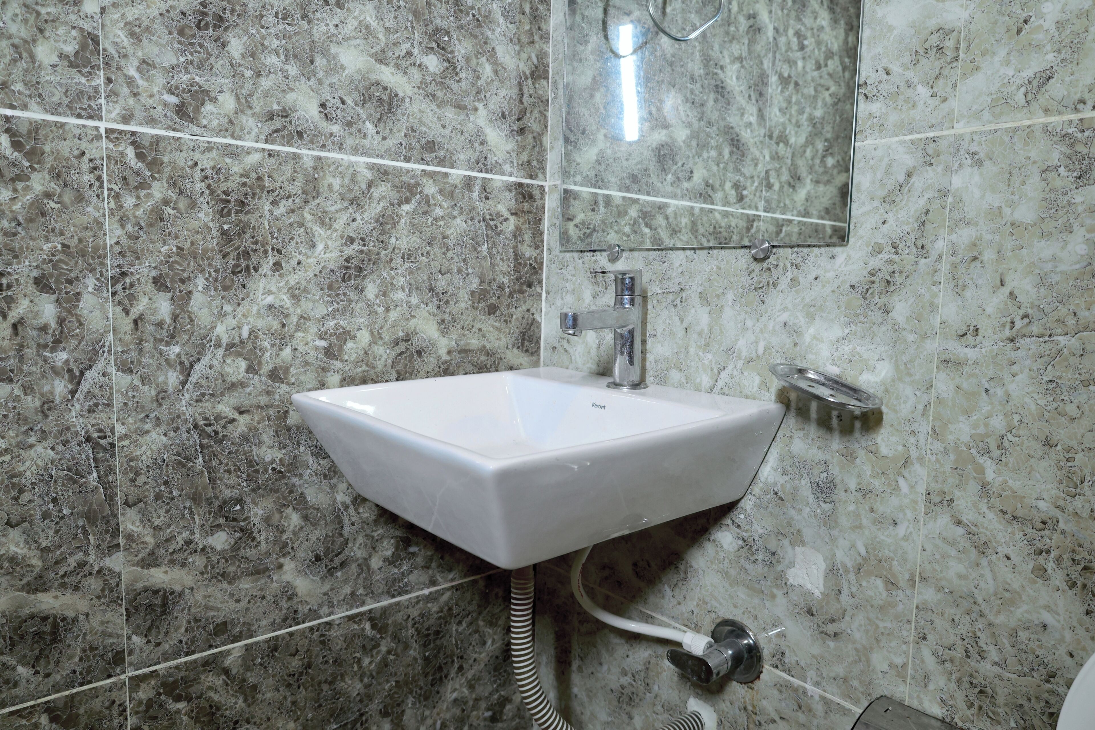 A bathroom with a white sink, a mirror, and a showerhead.