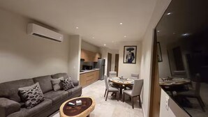 A modern living room with a sofa, coffee table, and dining area with chairs. - Sleek New Condo with Island Charm in Cozumel (Cozumel)
