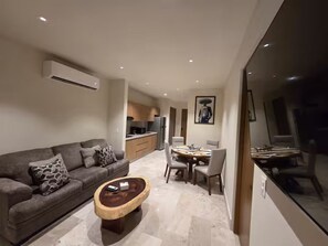 A modern living room with a sofa, coffee table, and dining area with chairs. - Sleek New Condo with Island Charm in Cozumel (Cozumel)