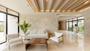 A modern living room with a sofa, chairs, a coffee table, and a large window. - Sleek New Condo with Island Charm in Cozumel (Cozumel)