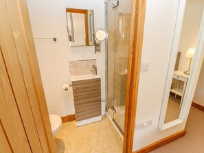 Ein Badezimmer mit Toilette, Waschbecken, Spiegel und Duschkabine aus Glas.
