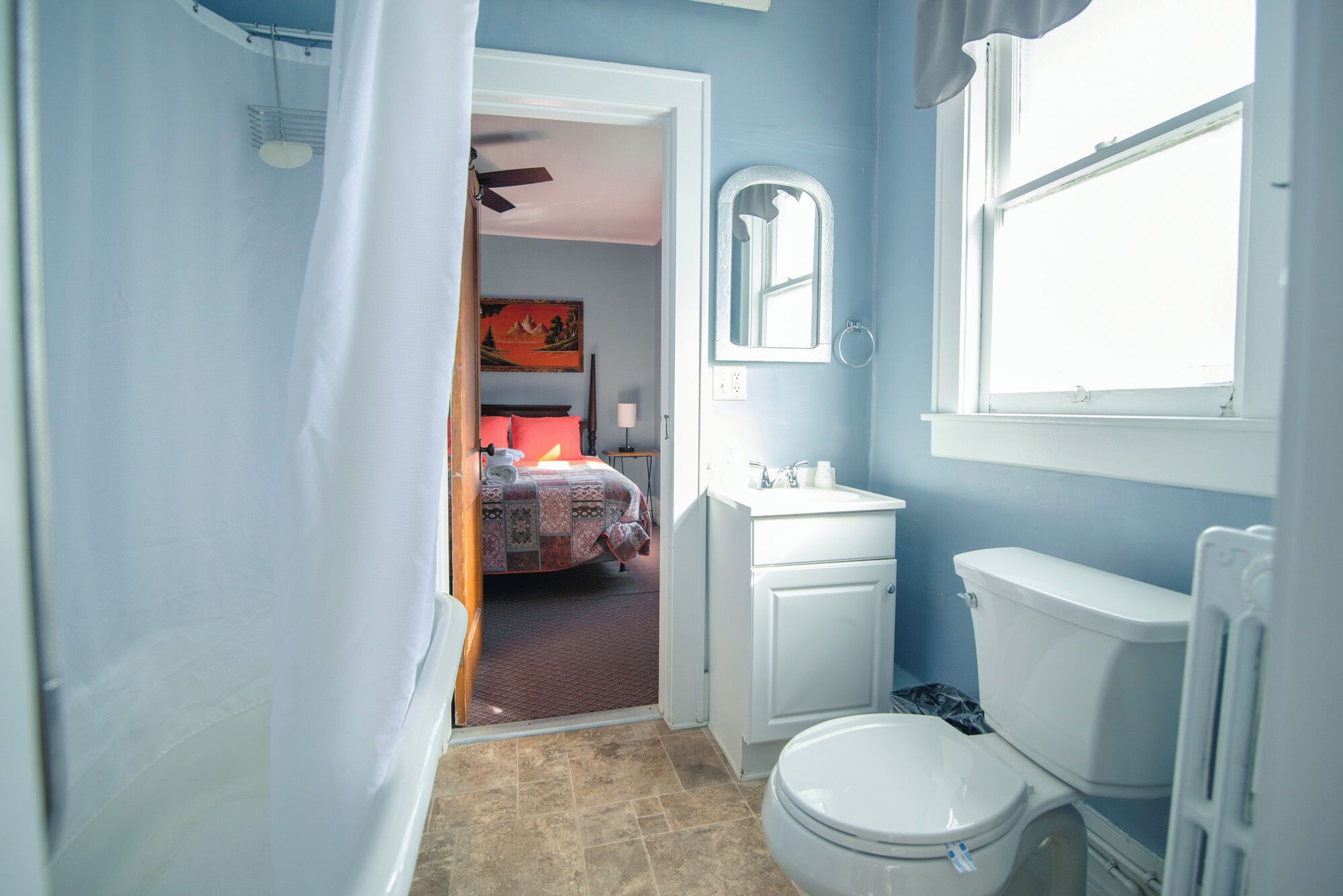 A bathroom with a toilet, sink, and mirror.