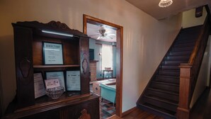 A directory on a wooden cabinet, a staircase, and a room with a window and a table. - Old Clark Inn (Marlinton)