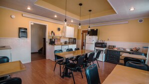A compact kitchen with a dining area, wooden flooring, and pendant lighting. - Old Clark Inn (Marlinton)