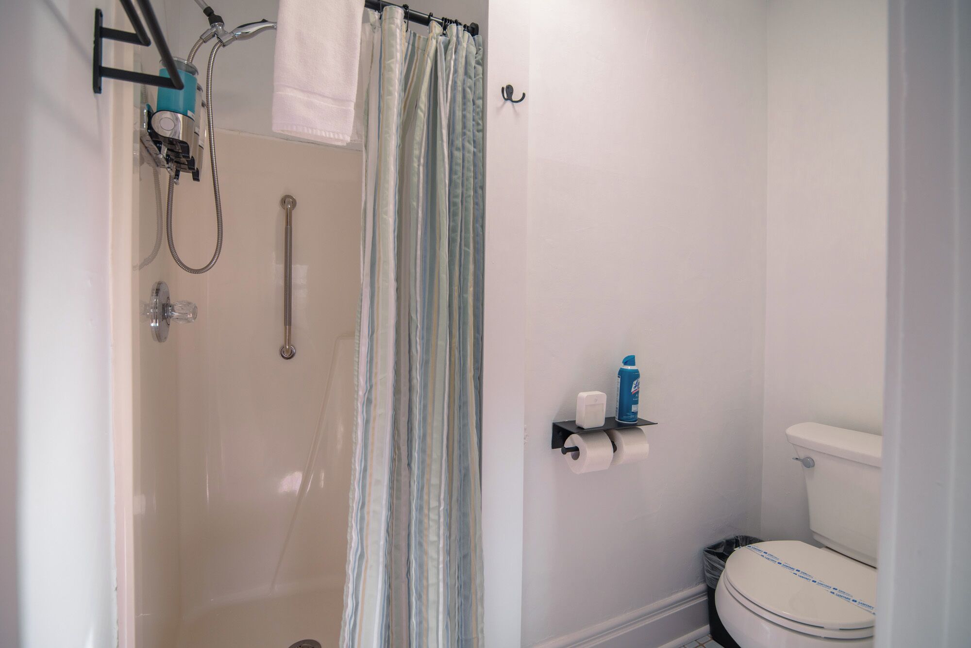 A bathroom with a shower, toilet, and a towel rack.