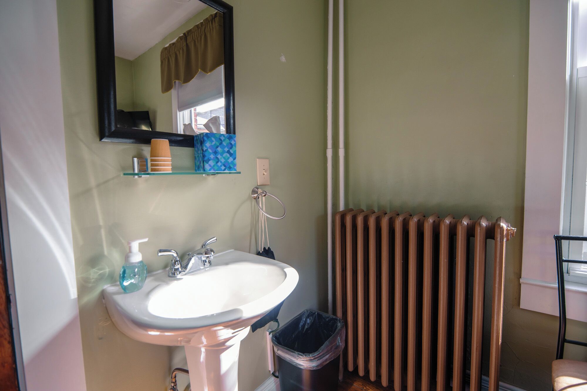Un baño con lavamanos, espejo y radiador.