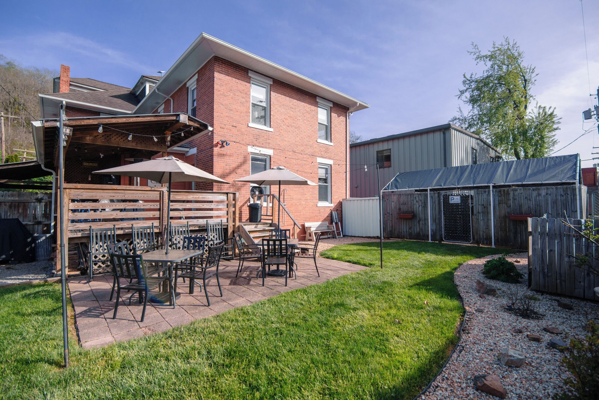 A patio with outdoor furniture, a brick building, and a fenced area.