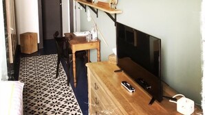 Une pièce avec un bureau en bois, une télévision, une chaise, un sol à motifs et des étagères remplies de divers objets.