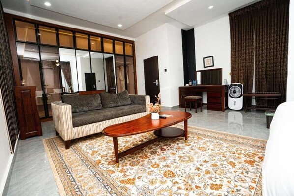 A living room with a sofa, coffee table, and a patterned rug. - The Mason By Trovardig (Abuja)