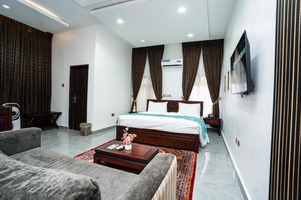 Una habitación de hotel con una cama grande, un sofá, una mesa de centro y un televisor montado en la pared.