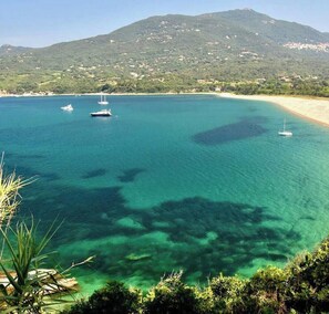 A coastal view with clear turquoise water, boats, and a mountainous backdrop. - Between the sea, the pool, and the maquis: a two-bedroom apartment with panoramic views   (Propriano)