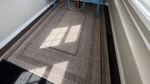 A room with a window, a blue chair, a small table, and a patterned rug. - Modern 2 Bed 1 Bath Friendly Morningside Area (Sioux city)