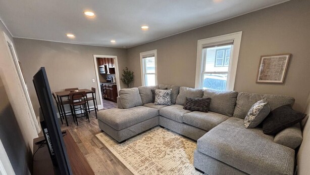 A living room with a sectional sofa, a flat-screen TV, and a dining area. - Modern 2 Bed 1 Bath Friendly Morningside Area (Sioux city)