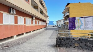 Um edifício com várias varandas, uma parede de pedra e um caminho pavimentado.