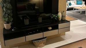 Un soggiorno moderno con una TV a schermo piatto, un divano, un tavolino da caffè e oggetti decorativi.