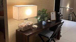 Una scrivania d'angolo con una lampada, una pianta in vaso e un certificato incorniciato.