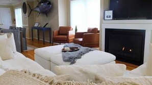Ein Wohnzimmer mit Kamin, weißen Sofas, einem Couchtisch und einer an der Wand befestigten Fischdekoration.