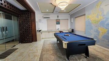 A pool table in a room with a map on the wall, a door, and a window.