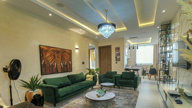 A modern living room with a green sofa, a round coffee table, and a chandelier. - The Enclave Apartment (Asaba)