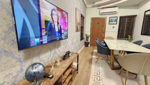 A conference room with a large flat-screen TV, a wooden coffee table, and a dining table with chairs. - The Enclave Apartment (Asaba)