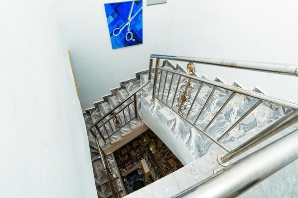 Un escalier en marbre avec des rampes en métal et une œuvre d’art bleue accrochée au mur.