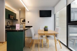 Eine moderne Küche mit einer zentralen Kochinsel, einem Essbereich mit Tisch und Stühlen sowie einem an der Wand befestigten Flachbildfernseher.