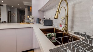 Une cuisine moderne dotée d’un évier en acier inoxydable, d’un four encastré et d’un plan de travail muni d’un égouttoir.