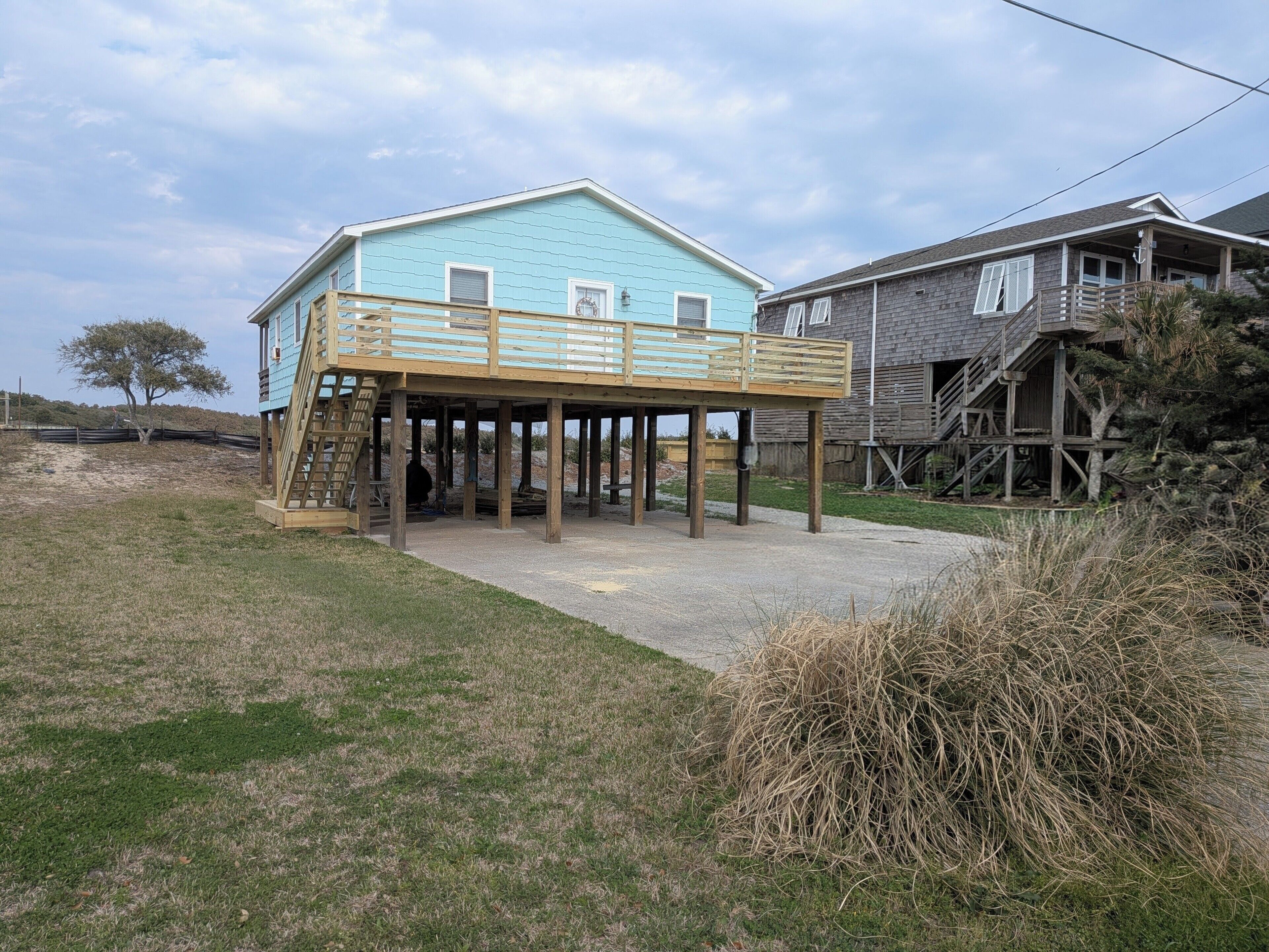 A two-story house with a wooden deck and a staircase leading to a balcony.