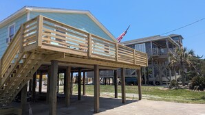 A wooden deck structure with a staircase leading to a covered area, supported by wooden posts.
