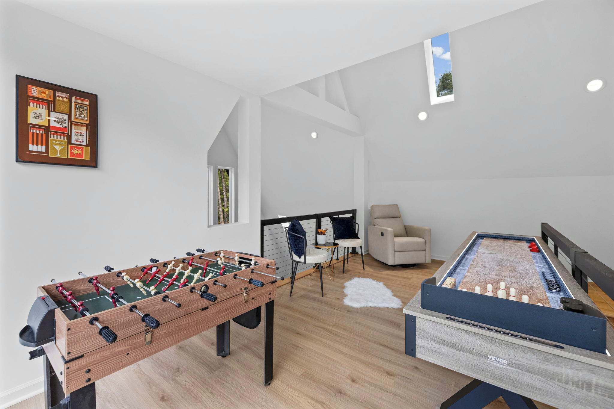 Ein modernes Wohnzimmer mit Kicker, Billardtisch und einer Sitzecke mit Sofa und Sesseln.