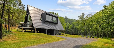 A modern house with a sloped roof, a covered deck, and a gravel driveway leading to the entrance.