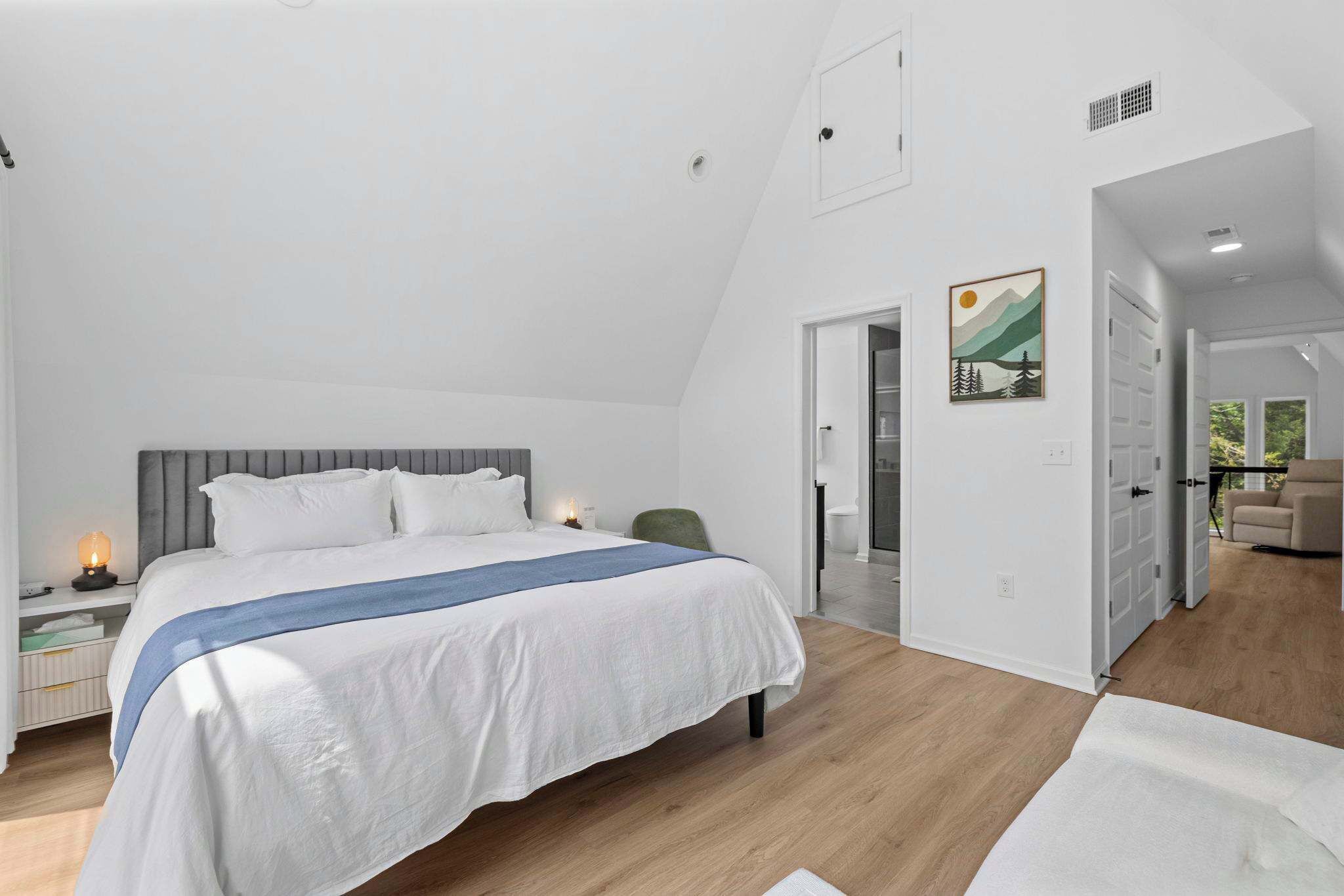 A bedroom with a bed, bedside table, and a nightstand with a lamp.